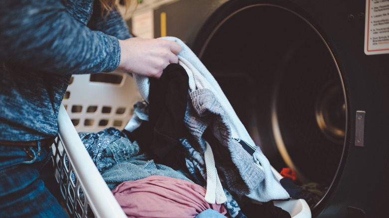Person putting dirty clothes in washer