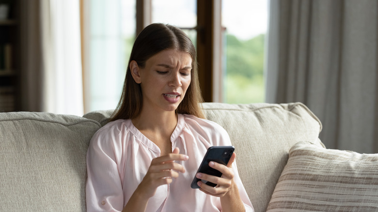 A frustrated woman is looking at her smart phone