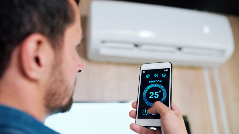 Man using his smart phone to control a smart AC