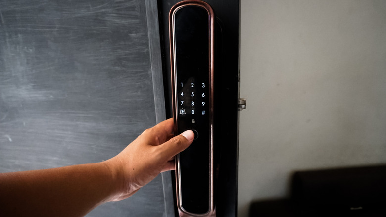 person holding a door handle with a smart keypad and fingerprint lock