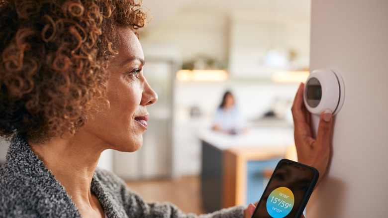 Woman controlling smart thermostat