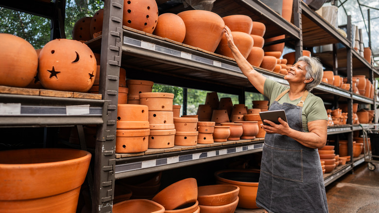 Woman at garden center checks on terracotta pots.