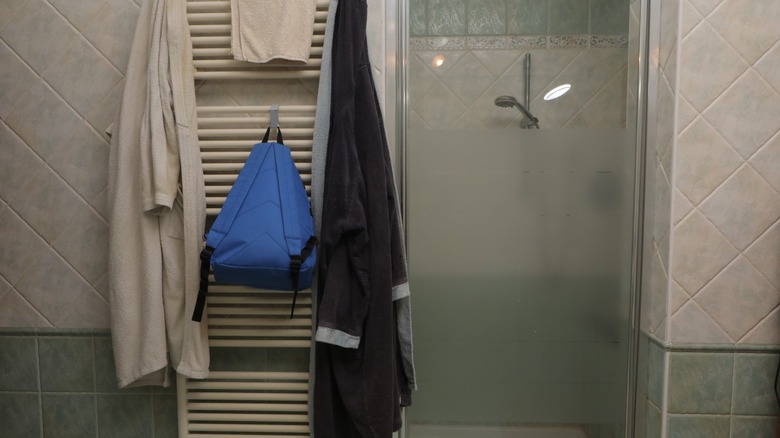 clothes, towels, and a bag taking up space on a towel warmer