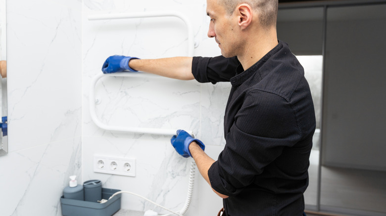 an expert installs the heating element of a towel warmer