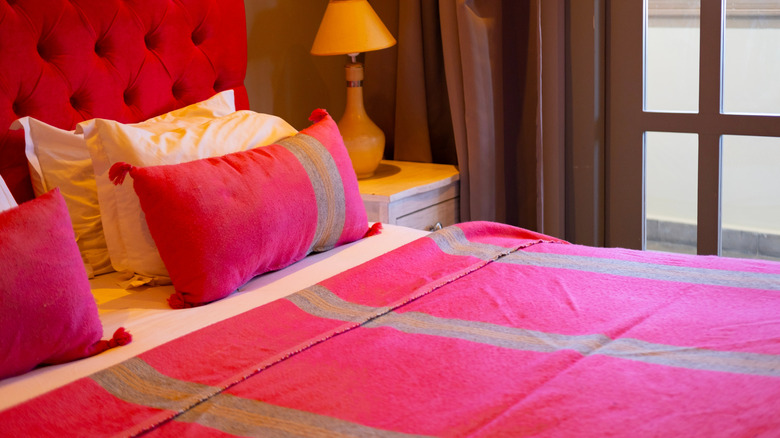 Hot pink bedding linens, pillows, and headboard in bedroom
