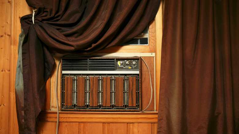 A brown vintage A/C unit behind a brown curtain.