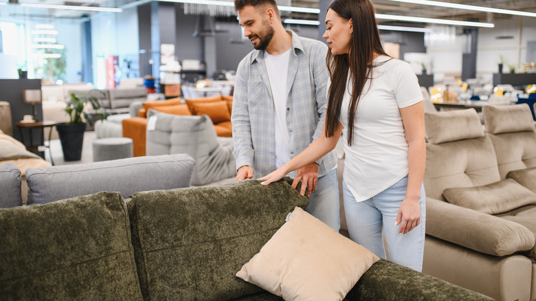 A man and woman looking at sofas in a store.