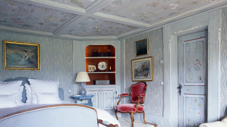 A blue bedroom with wallpapered ceilings