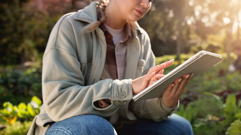 Woman holds tech device in the garden