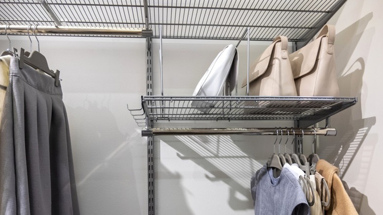 wire closet shelves holding handbags and hanging clothes