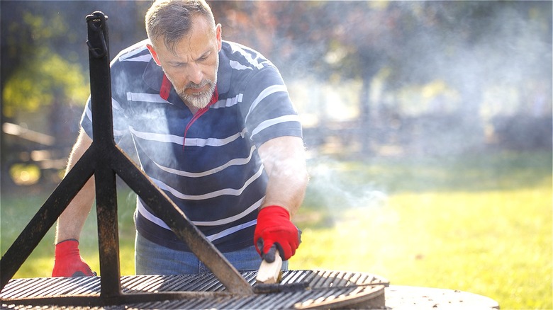 Person scrubbing hot grill outdoors