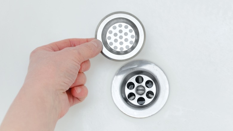 Hand holding metal shower drain cover
