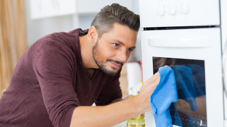 Man cleans oven exterior