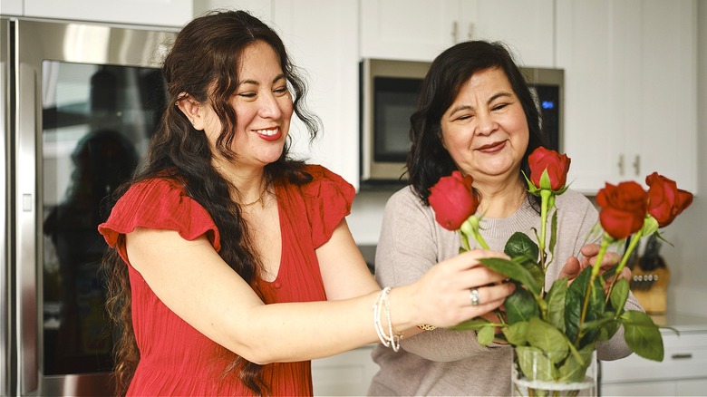 People arranging flowers in kitchen