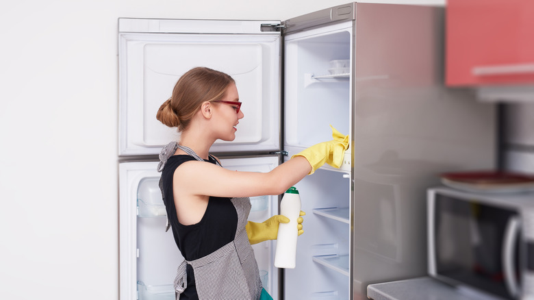 Person wiping down fridge interior