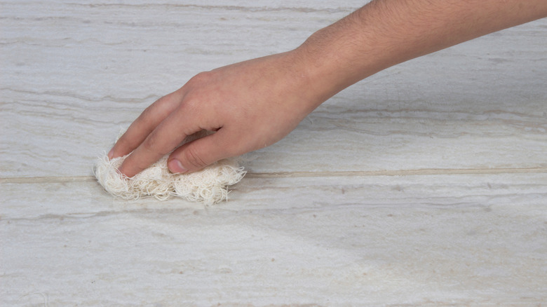 A person's hand applying sealant to a grout line