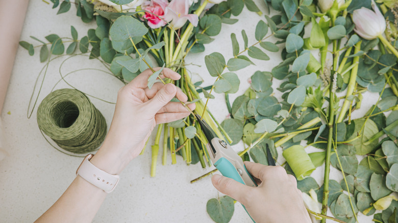 Person cutting leaves off flowers