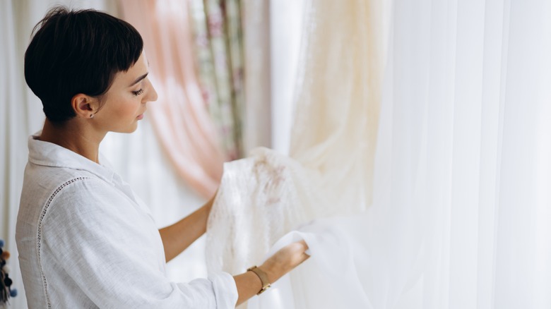 A woman examines curtains in a showroom.