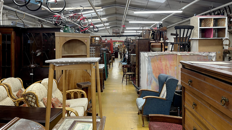 A thriftstore filled with used furniture of all shapes and sizes, including chairs, hutches, dressers, and wardrobes