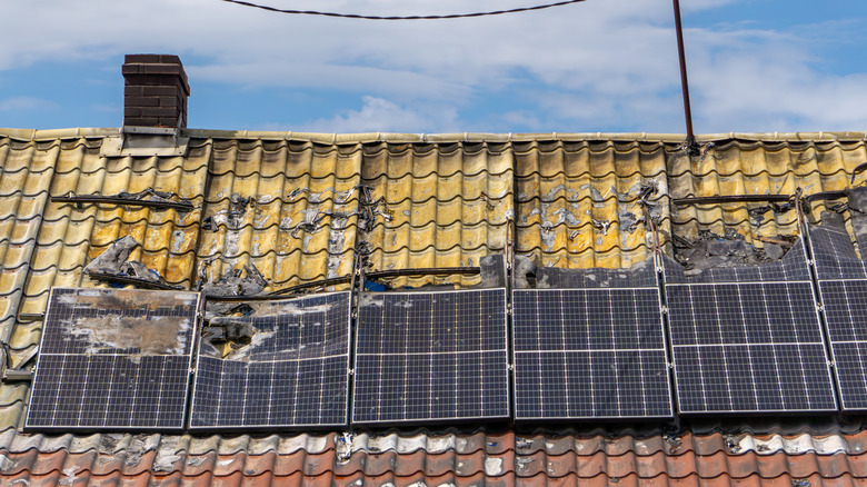Old damaged solar panels on the roof of a house.