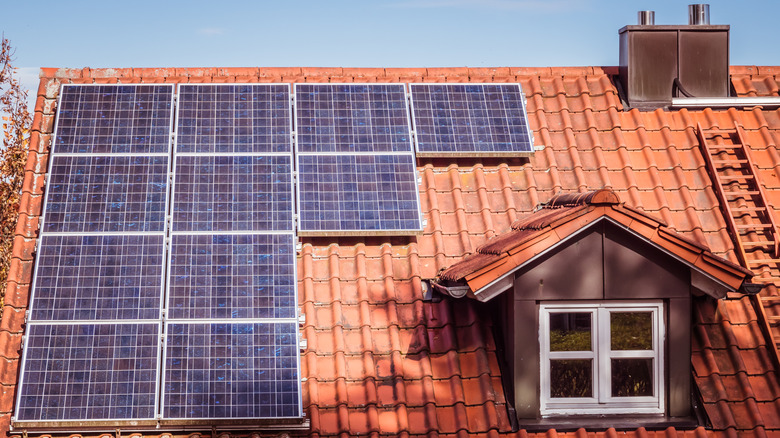 Solar panels installed on the brick-tiled roof of a house.