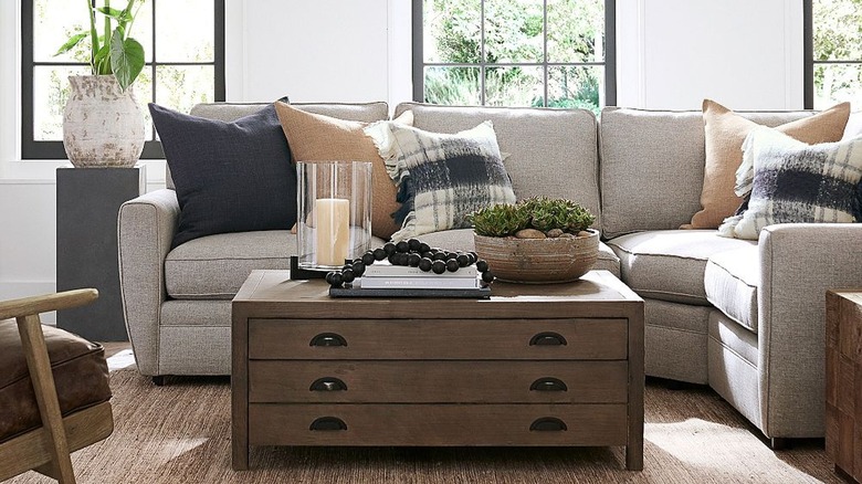 Wooden decor beads draped over stacked books next to candle and plant.