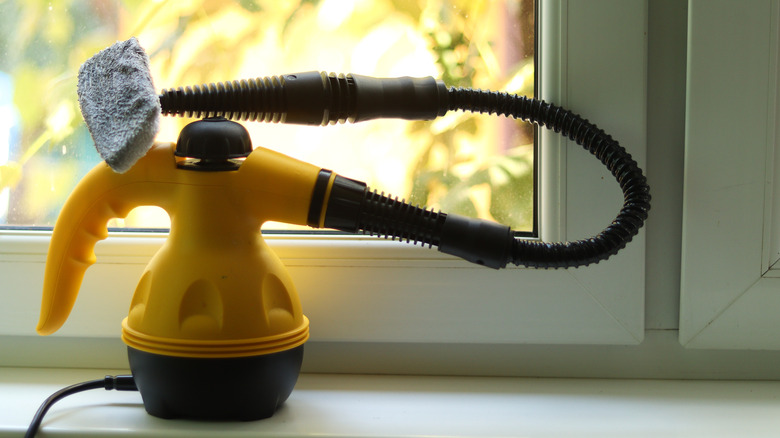 A yellow steam cleaner sitting on a windowsill