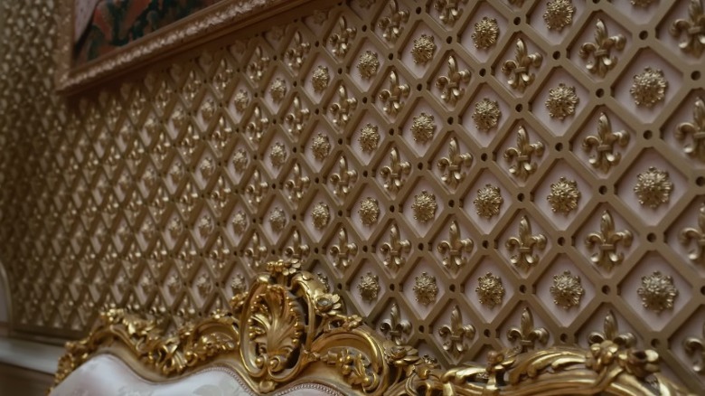 Guilded lattice wall applique with fleur-de-lis and flower shapes in gold