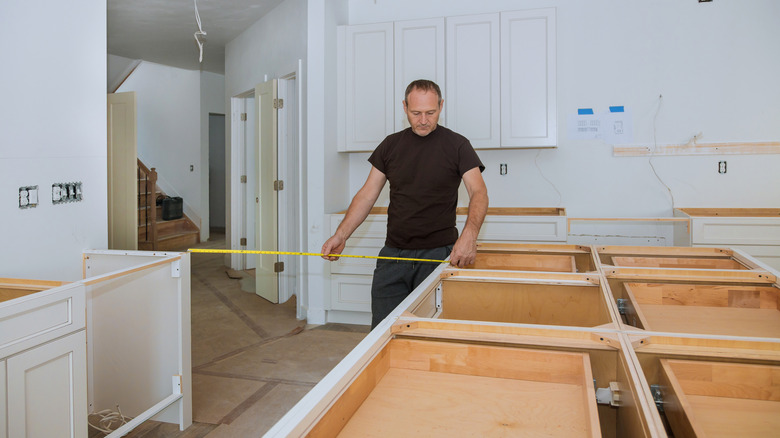 Contractor measuring distance between kitchen cabinets and island