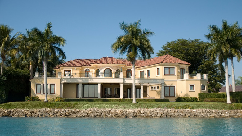 The exposed backyard of a large coastal home beside a calm inlet.