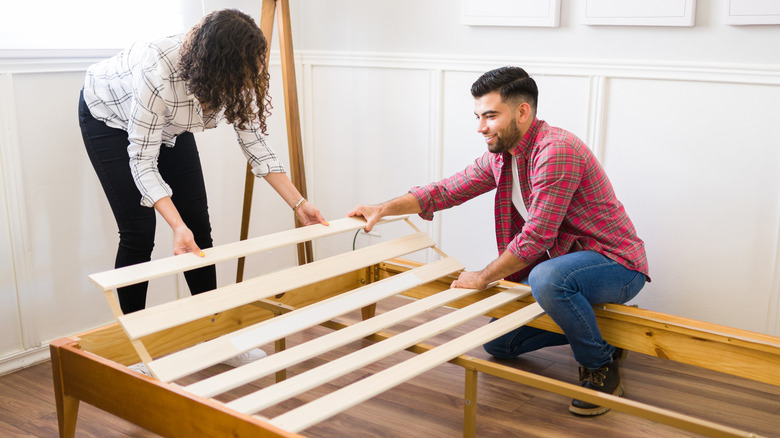 Couple putting wood bed frame together