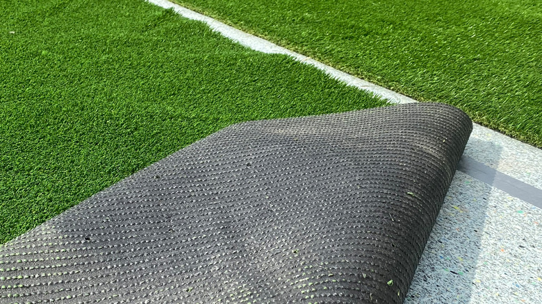 Artificial turf rolled up at the corner during installation.