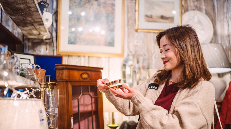 A woman looking at a dish in an antique shop