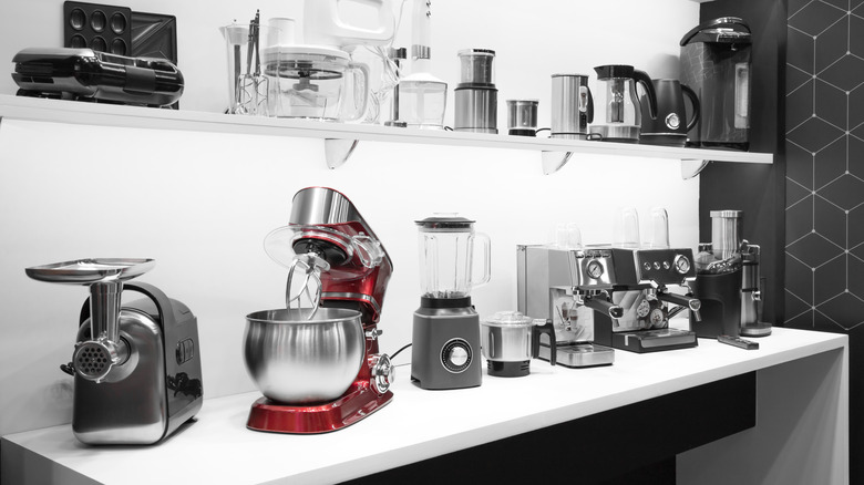 Shelves filled with various kitchen appliances including mixers, blenders, griners, kettles, and more