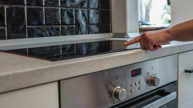 Person pointing to a glass stovetop