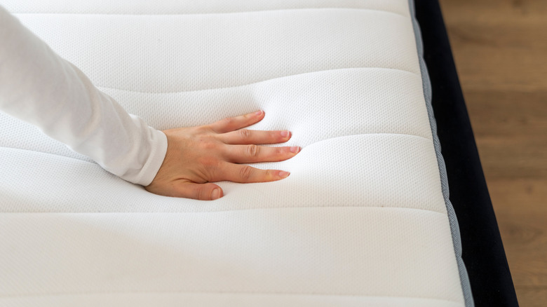Cropped shot of a hand testing new orthopedic memory foam core mattress