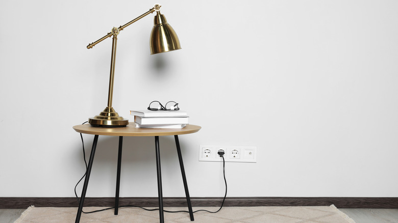 gold finish industrial lamp on side table with books and glasses