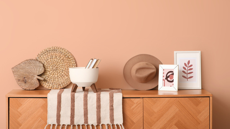 Muted coral wall with a console table with decor displayed