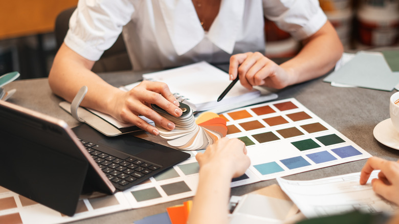 Hands choosing paint colors from swatches on a table
