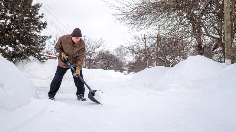A man shovels a heavy amount of snow from his driveway.