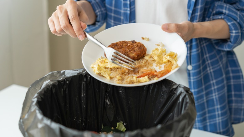 Raschiare gli avanzi di cibo nella spazzatura