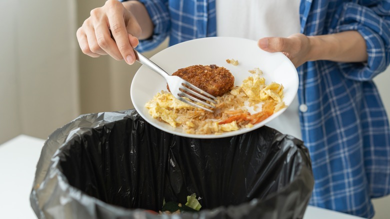 Scraping leftover food into trash