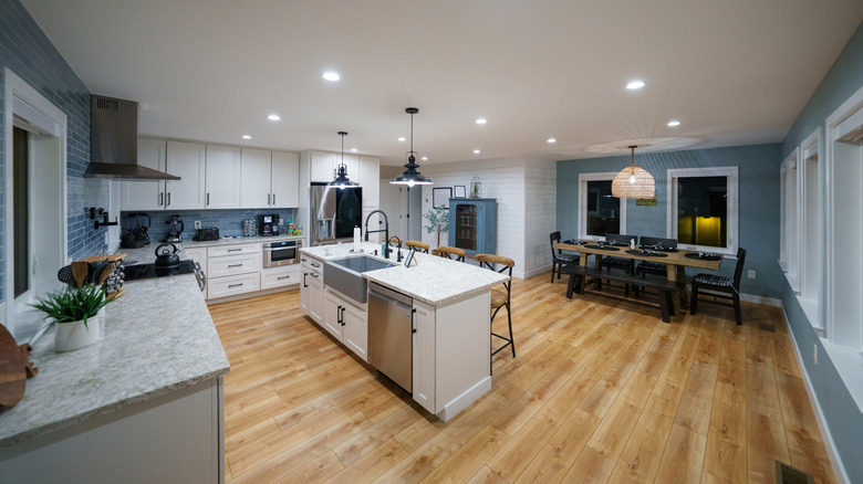 A wide shot of a modern farmhouse kitchen and dining room with island and wooden floors