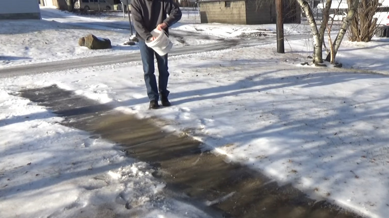 a man spreads sand on a path as a de-icer