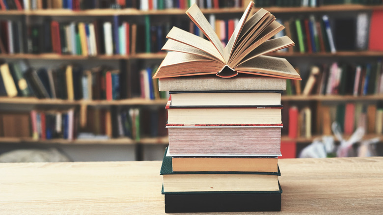 Stack of books on a table with the top book's pages fanned