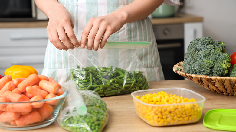 Woman placing vegetables into a clear plastic storage bag