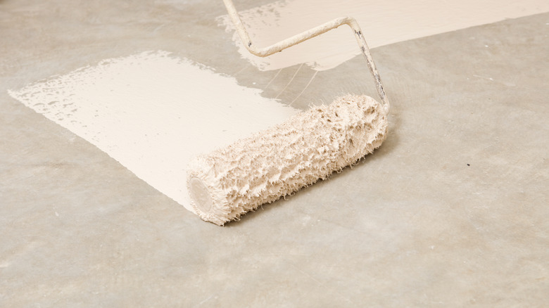 Warm white paint on paint roller, painting on a gray surface