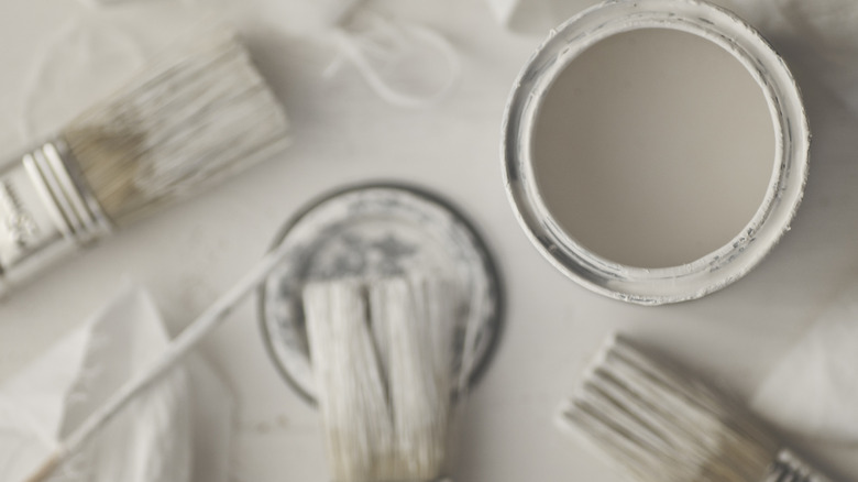 Can of white paint with paint brushes
