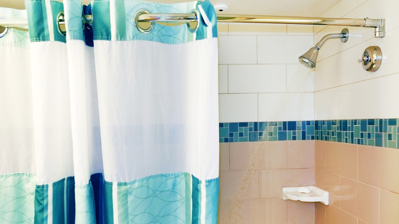 A white and blue shower curtain hanging on a gold metal rod