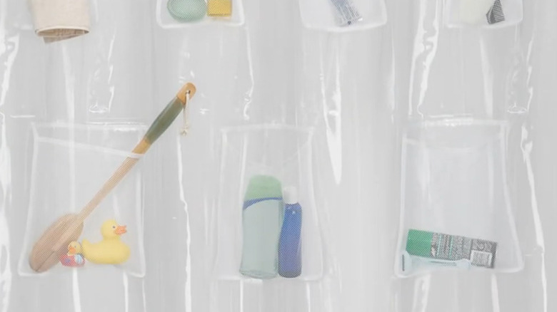 A white shower curtain with mesh storage pockets containing bathroom items